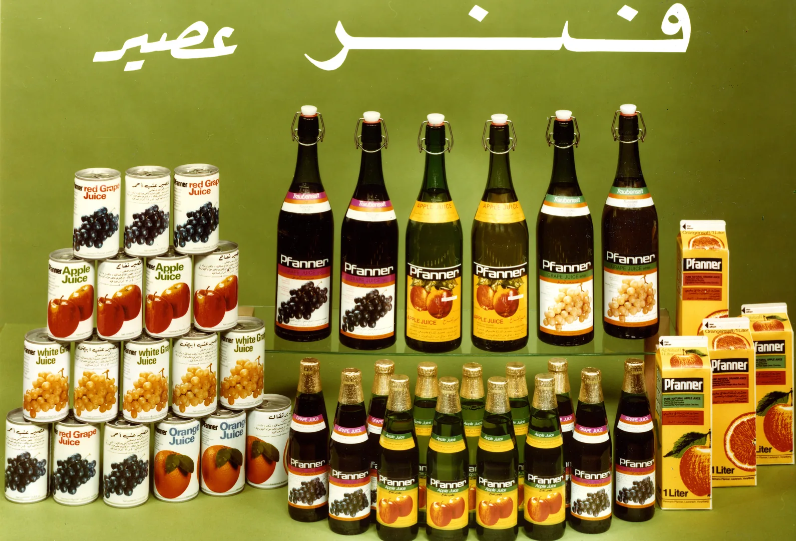 Produktschau des Pfanner-Exportsortiments: Dosen, Bügelflaschen und Kartons mit Apfel-, Trauben- und Orangensaft, teils mit arabischer Beschriftung.